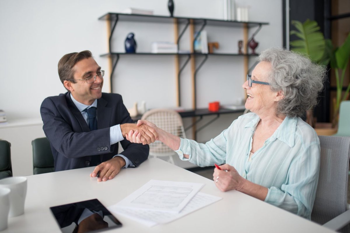A consultant shaking hands with a client across a desk